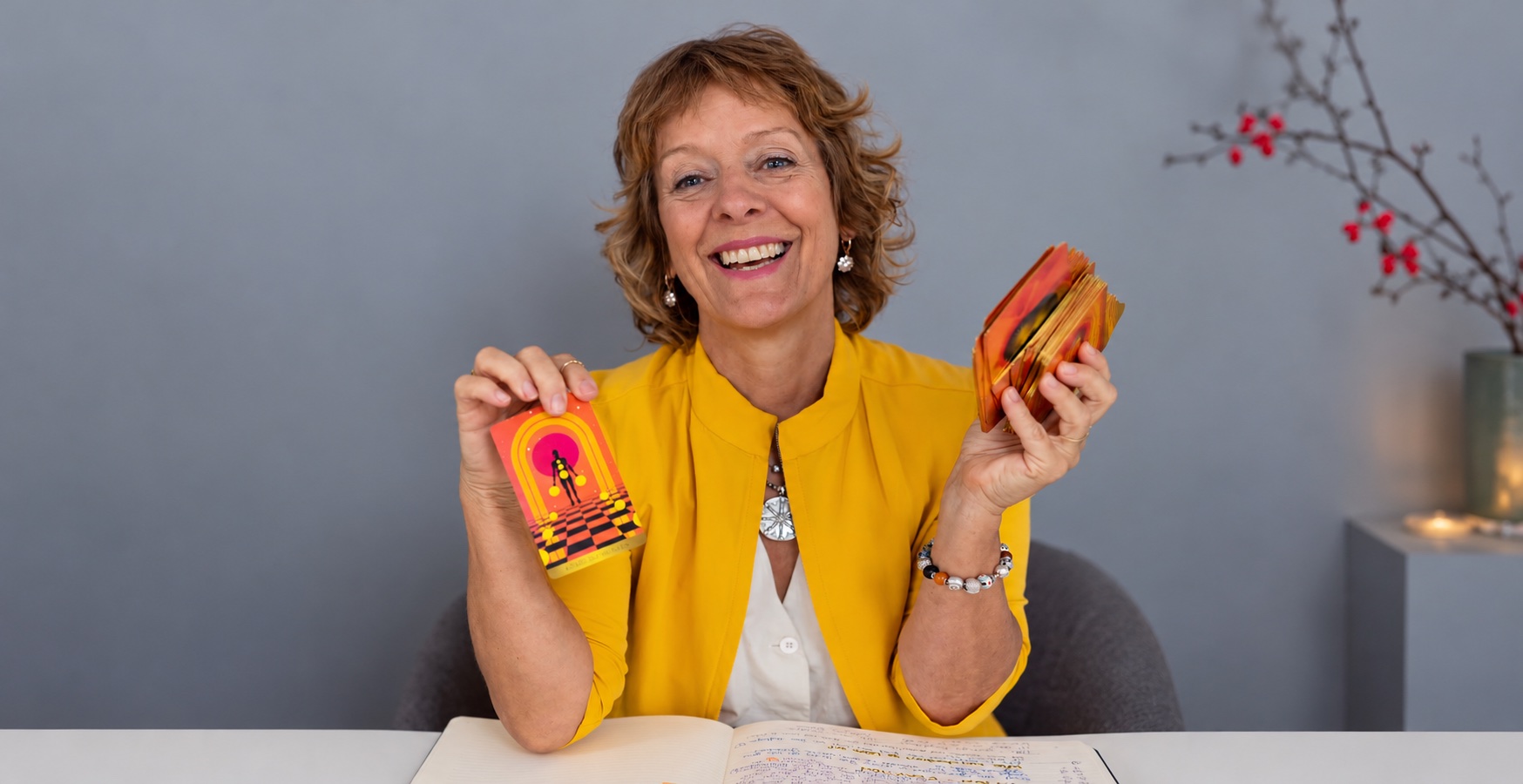 Claudia Fornito lacht am Tisch und hält farbige Inspirationskarten in den Händen