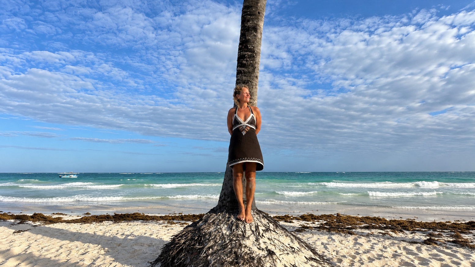 Claudia Fornito lehnt an einer Palme an einem weissen Sandstrand