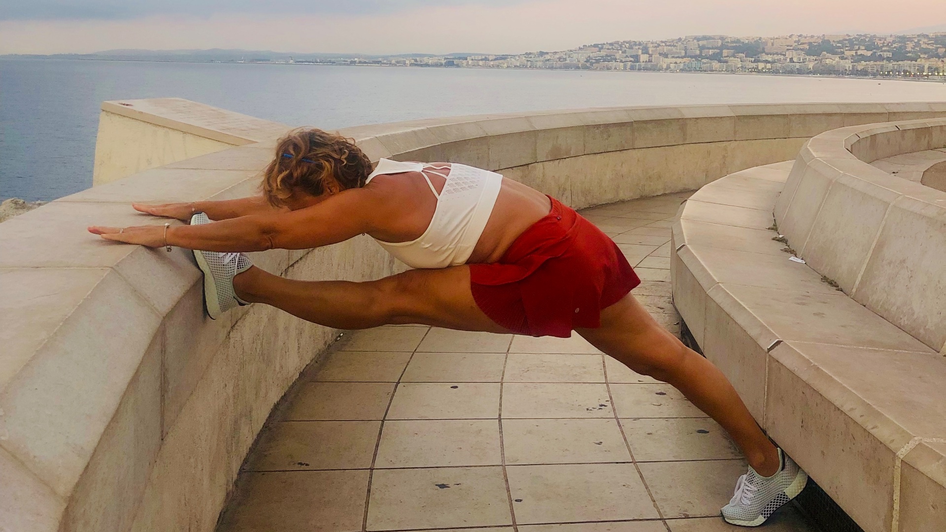 Claudia Fornito dehnt sich auf einer Promenade am Meer