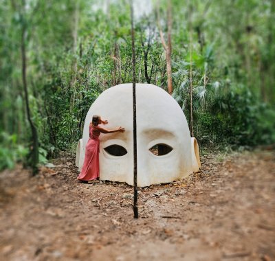 Claudia Fornito berührt eine grosse Kopfskulptur im Wald